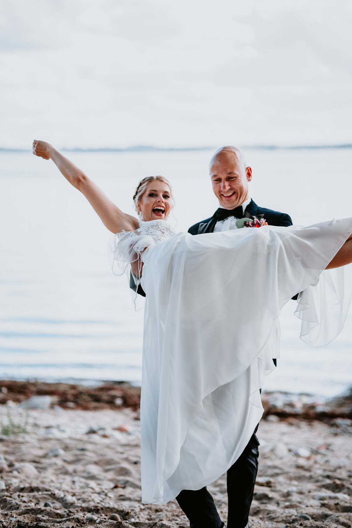 Hochzeitsfotograf Schleswig-Holstein – Jasper von Harlem Brautpaar am Ostseestrand in Schleswig-Holstein, die Braut wird vom Bräutigam lachend hochgehoben